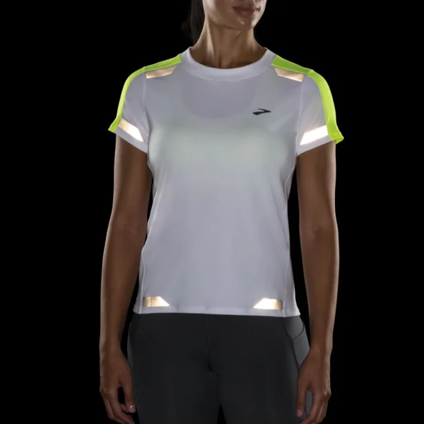 Juoksija käyttää Brooks Women's Run Visible Short Sleeve -juoksupaitaa iltalenkillä hämärässä.